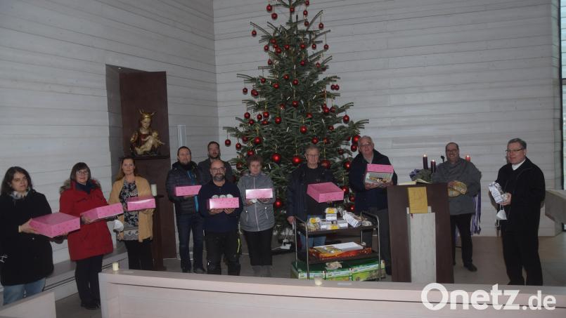 Reinhold Birner (Dritter von rechts) vom Netzwerk Asyl sowie Engelbert Mayer (Vierter von rechts) von der Tafel nehmen die süßen Spenden erfreut entgegen. Bild: fz