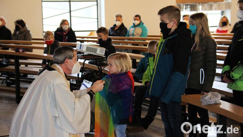 Pfarrer Werner Sulzer (links) legt den Kindern und Jugendlichen beim Segensakt ein Tuch über die Schultern. Bild: bjo