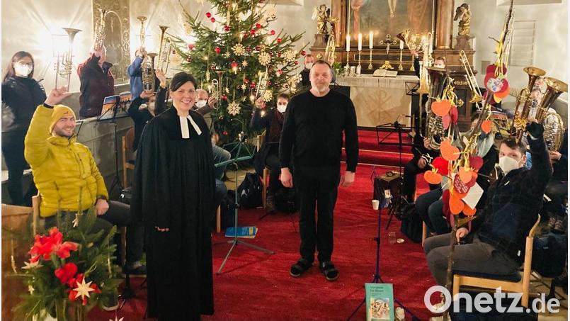 Die Chormitglieder heben ihre Instrumente, als Pfarrerin Anja Matthalm den Posaunenchorleiter Kai Berendes (Mitte) verabschiedet. Bild: Evangelische Kirchengemeinde Neukirchen/exb
