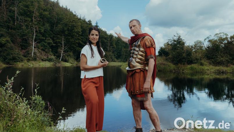 Cäsar (Thorsten Krohn) trifft am Rubikon eine folgenschwere Entscheidung. Für diesen Moment in der Geschichte haben die Mitarbeiter der IFAGE Filmproduktion nach einem passenden Fluss gesucht: Die Naab in der Nähe des Anglerheims in Nabburg entpuppte sich als ideal. Clarissa Corrêa da Silva (links) sucht dort den Römer mit Hilfe der Zeitmaschine persönlich auf, um ihn zu interviewen. Bild: Sabine Finger/exb