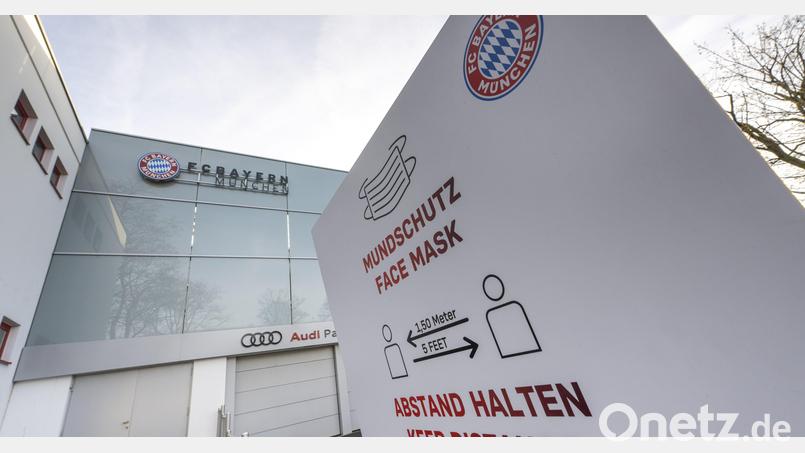 Das Logo des FC Bayern München und der Hinweis auf Mundschutz und Abstandsregel sind auf einem Schild vor dem Hauptgebäude des Fußball-Vereins zu sehen. Auf dem Gelände wird strikt auf die Corona-Regeln geachtet, privat gehen die Profis wohl eher lax damit um. Bild: Peter Kneffel