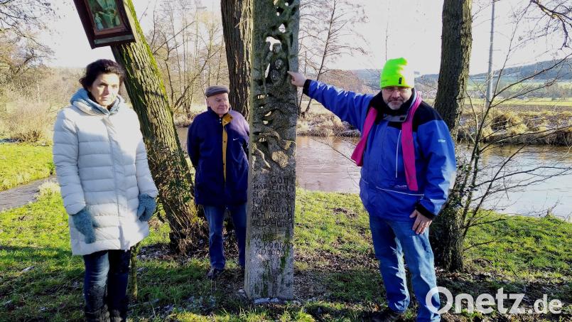 Michael Träger zeigt auf die in Stein gemeißelten Gesichter im Bildstock, die von Unbekannten beschädigt wurden. Bild: Kunz