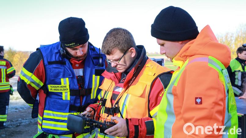 Der Gruppenführer (blaue Weste, links) sieht zusammen mit dem Piloten (orange Weste, Mitte) und dem Ausbilder (rechts) auf die Fernbedienung; dort wird ebenfalls das Bild der Drohne übertragen. Bild: egl