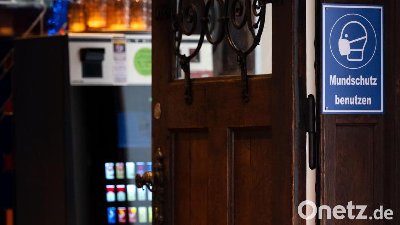 Ein Schild mit der Aufschrift "Mundschutz benutzen" ist am Eingang eines Wirtshauses zu sehen. Symbolbild: Sven Hoppe/dpa