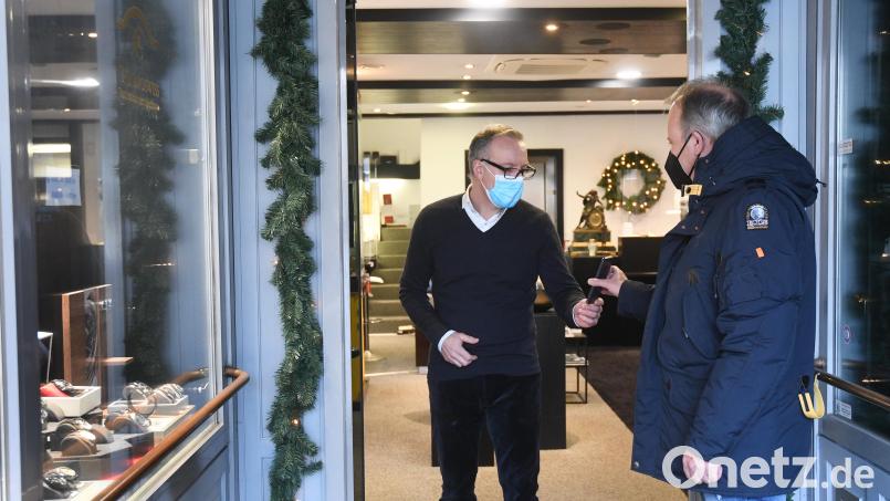 Michael Sebald kontrolliert an der Eingangstür seines Ladens in der Weidener Altstadt bei einem Kunden die 2G-Regel. Bild: Gabi Schönberger