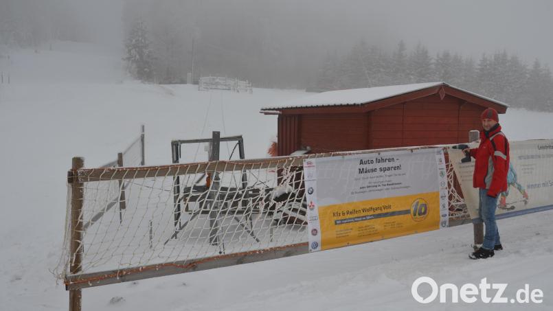 TSV-Abteilungsleiter Christian Enslein aus Pleystein schraubt die Werbebanner am Kinderlift an. Bild: dob