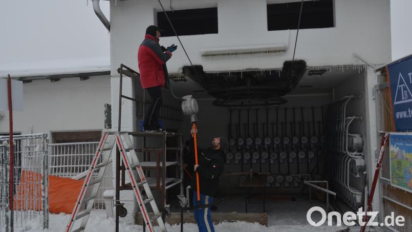 Helfer bringen mit Liftbetreuer Andreas Gmeiner (rechts) die Liftbügel am Skilift an. Bild: dob