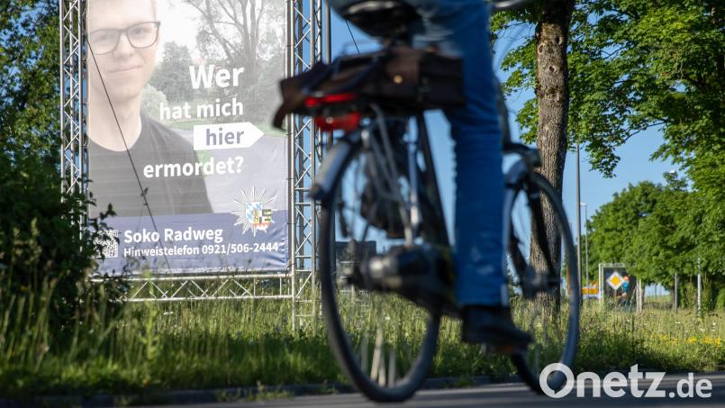 "Wer hat mich hier ermordet?" steht auf einem großen Plakat mit Foto des Opfers neben dem Tatort. Die Polizei streicht nun einen weiteren Verdächtigen. Bild: Daniel Karmann