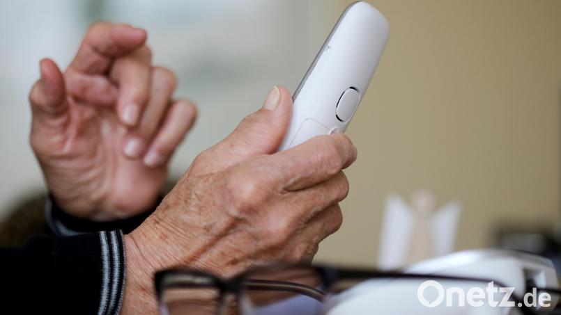 Eine ältere Dame nimmt in ihrer Wohnung ein Telefongespräch an. Immer wieder gelingt es falschen Polizeibeamten, Menschen dazu zu bringen, ihnen Geld oder Wertgegenstände auszuhändigen. Symbolbild: Roland Weihrauch/dpa