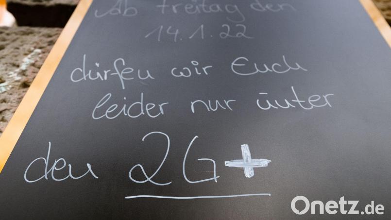 Auf einem Schild wird vor einem Cafe auf die 2G-plus-Regel hingewiesen. Wer genesen ist, behält diesen Status künftig nur noch drei statt sechs Monate. Foto: Robert Michael/dpa-Zentralbild/dpa Bild: Robert Michael