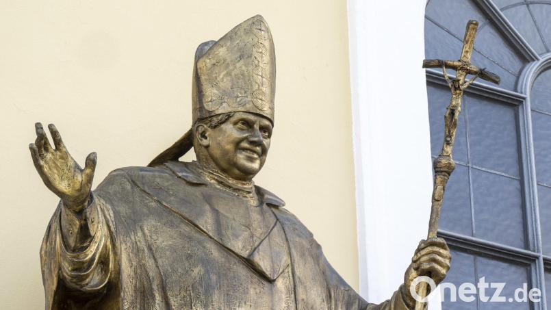 Eine Figur des emeritierten Papstes Benedikt XVI. hängt an einer Fassade am Kapellenplatz im Zentrum von Altötting. Ein Missbrauchsgutachten im Auftrag des Bistums München belastet ihn in seiner Zeit als Erzbischof schwer. Archivbild: Peter Kneffel/dpa