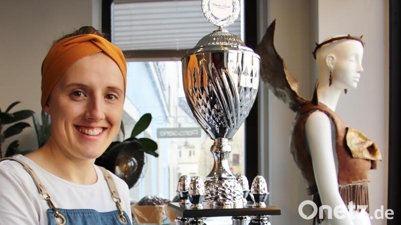 Konditor-Meisterin Carolin Brunner ist jetzt ein beglaubigter &quot;Master of Sweets&quot;, wie man der Aufschrift des großen Siegespokals entnehmen kann. Dieser Pokal und das Kleid aus Schokolade (im Hintergrund) sind im Schaufenster von Brunners Café auf dem Marktplatz in Schwandorf zu bestaunen. Bild: Thomas Dobler