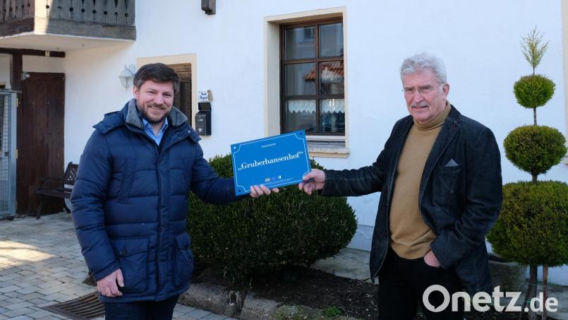 Bürgermeister Peter Neumeier (links) übergibt das Hausnamenschild (Gruberhansenhof) an Eigentümer Manfred Röhl. Bild: mab