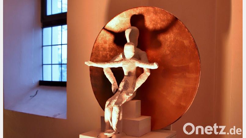 Das Kunstwerk &quot;Praesentatio&quot; von Markus Meier steht im Eingangsbereich der Klardorfer Pfarrkirche St. Georg. Samt Sockel ist das weiß gehaltene Werk etwa mannshoch, im Mittelpunkt sind zweisitzende Figuren vor vor einer konkaven, goldfarbenen Schale. Bild: Thomas Dobler