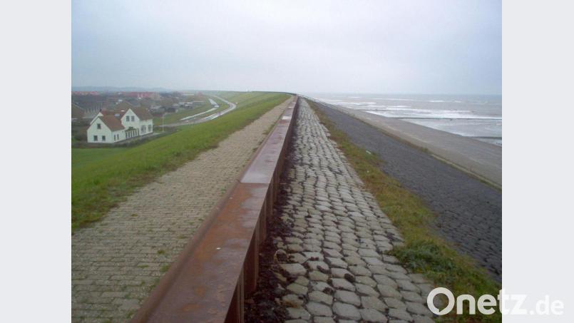 Ein Ort liegt an einem Deich hinter einem Strand in den Niederlanden. Bild: picture alliance / dpa