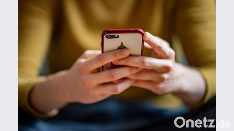 Eine junge Frau hält ein Smartphone in der Hand. Bild: Fabian Sommer/dpa/Illustration