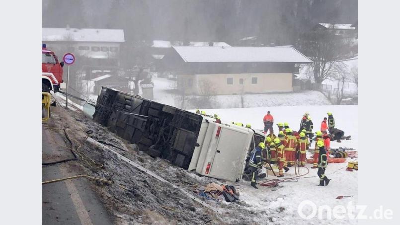 Einsatzkräfte der Feuerwehr stehen auf der Bundesstraße B306 am Ortsausgang von Inzell (Landkreis Traunstein) neben einem umgekippten Reisebus am Straßenrand. Bild: Kreisfeuerwehrverband Traunstein/dpa