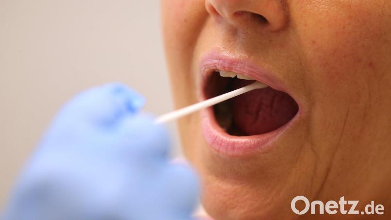 Ein Arzt nimmt in einer Hausarztpraxis mit einem Tupfer einen Abstrich bei einer Frau für einen Coronatest. Symbolbild: Karl-Josef Hildenbrand/dpa