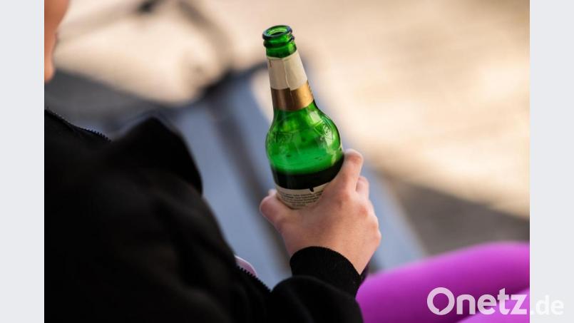 Ein jugendliches Mädchen hält vor ihrem Haus eine Flasche Bier. Bild: Silas Stein/dpa/Illustration