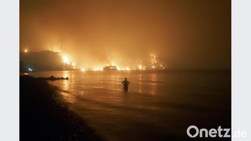 Ein Mann beobachtet, wie sich Waldbrände dem Strand von Kochyli in der Nähe des Dorfes Limni auf der Insel Evia (Griechenland) nähern. Bild: Thodoris Nikolaou/AP/dpa