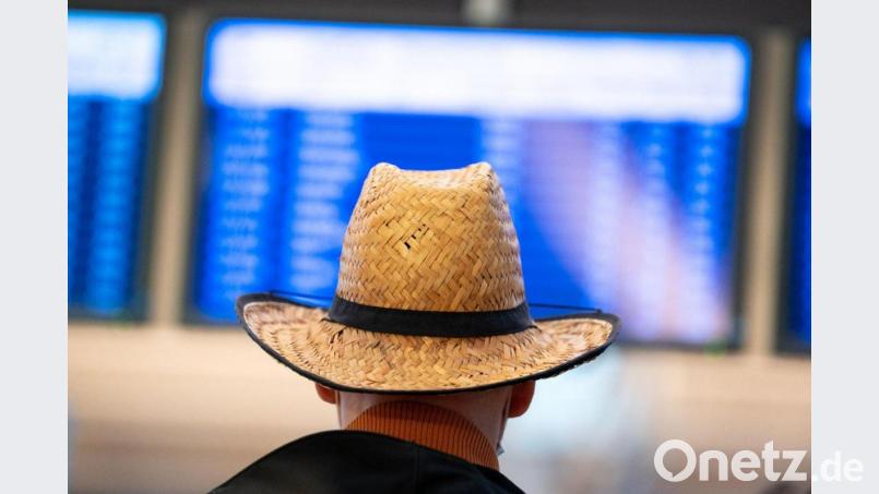 Ein Urlauber schaut auf die Abflugtafel in Hamburg. Bild: Jonas Walzberg/dpa