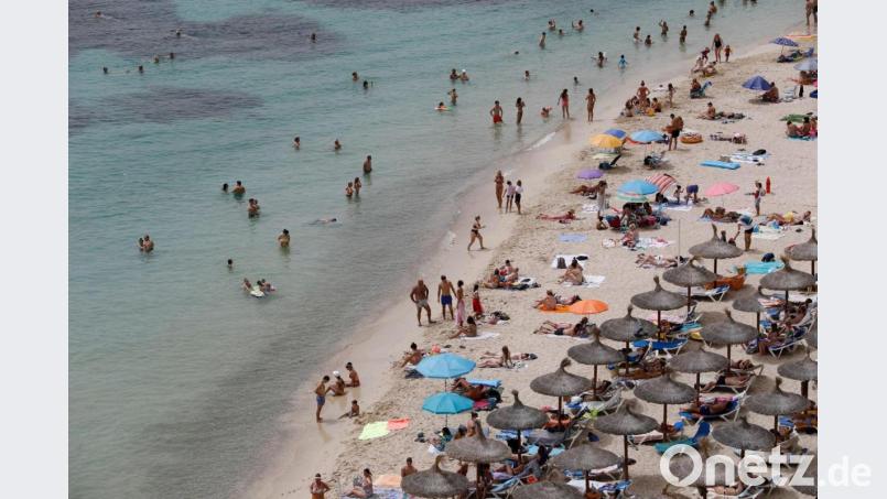 Touristen genießen an einem Strand bei Puerto Portals auf Mallorca die Sonne und das Meer. Bild: Clara Margais/dpa