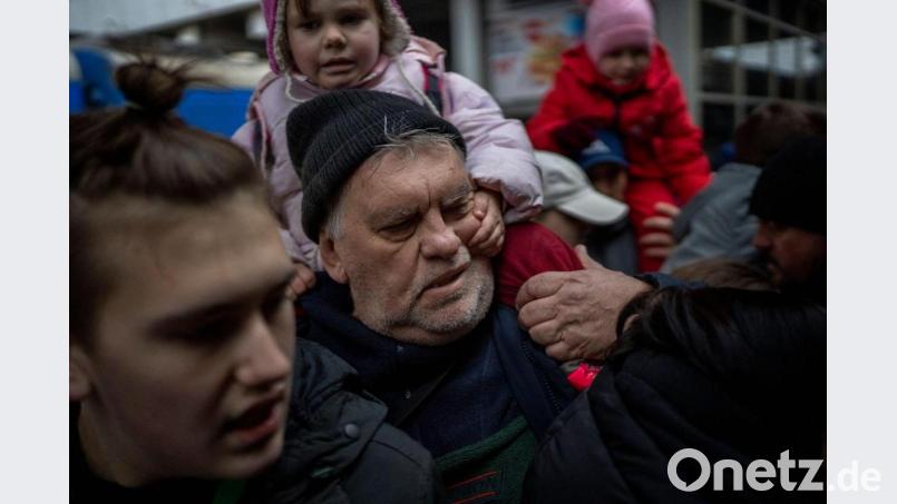 Ein Mädchen hält sich am Gesicht ihres Großvaters fest, während sie am Bahnhof von Kiew versuchen, in einen Zug nach Lwiw zu steigen. Bild: Emilio Morenatti/AP/dpa