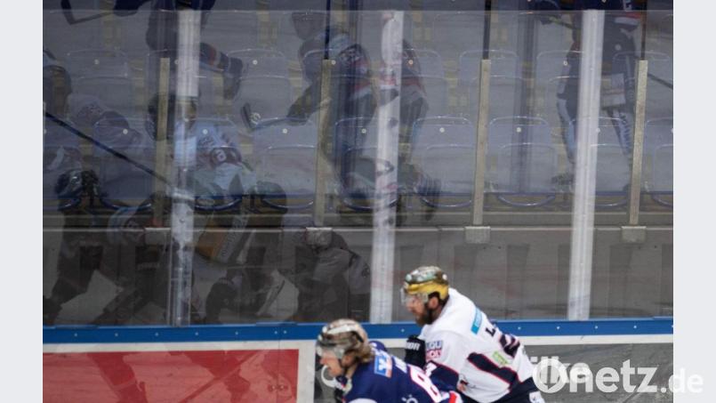 Eishockeyspieler spiegeln sich vor leeren Rängen in der Bande. Bild: Bernd Thissen/dpa/Symbolbild