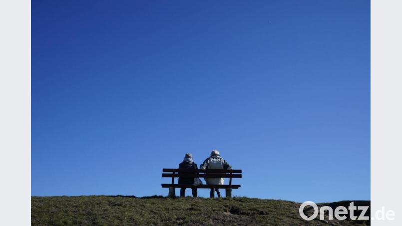 Ein älteres Paar bei strahlend blauem Himmel und Sonnenschein auf einer Bank an der Kieler Förde. Bild: Marcus Brandt/dpa