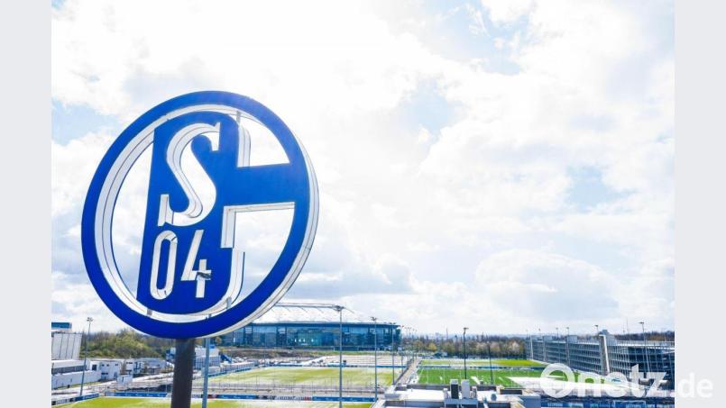 Im Vordergrund dreht sich das Logo des FC Schalke auf der Geschäftsstelle, im Hintergrund steht die Veltins-Arena. Bild: Guido Kirchner/dpa