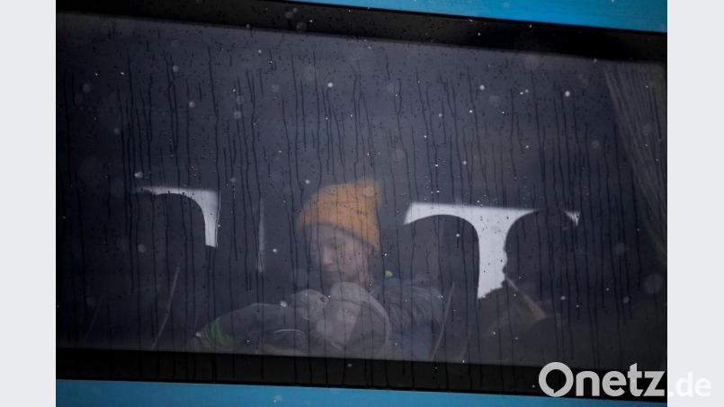 Eine Frau, die aus der Ukraine geflohen ist, hält ein Baby im Arm, während sie in einem Bus an der rumänisch-ukrainischen Grenze sitzt. Bild: Andreea Alexandru/AP/dpa