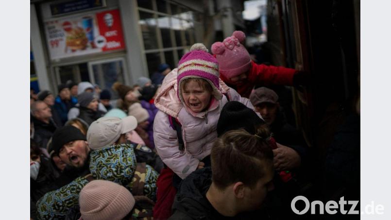 Menschen tragen ihre Kinder und versuchen am Bahnhof von Kiew in einen Zug nach Lwiw zu steigen. Bild: Emilio Morenatti/AP/dpa