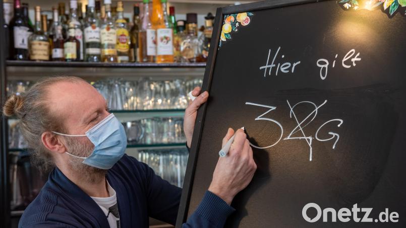 Ein Gastronom passt eine Informationstafel an. Bild: Stefan Puchner