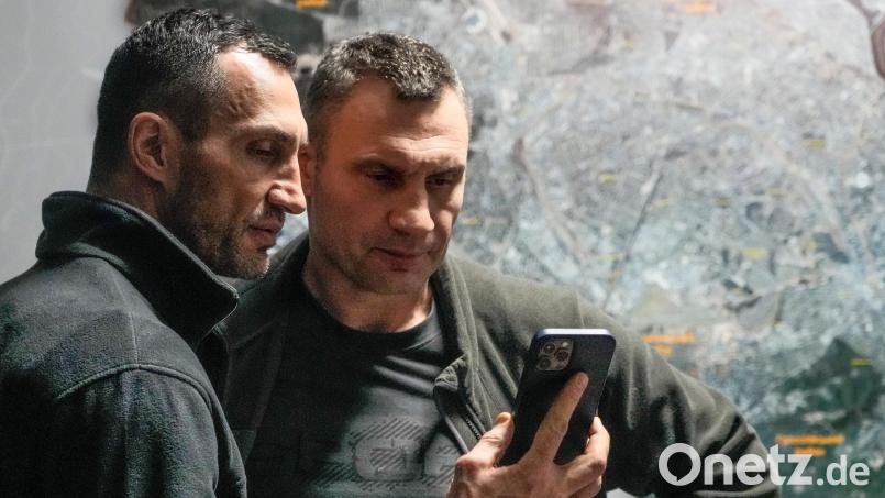 Vitali Klitschko (rechts), Bürgermeister von Kiew und ehemaliger Box-Profi, und sein Bruder Wladimir Klitschko, ebenfalls ehemaliger Box-Profi, schauen auf ein Smartphone im Rathaus in Kiew. Ein Film über die Brüder wird im Cineplex Amberg gezeigt. Archivbild: Efrem Lukatsky/dpa