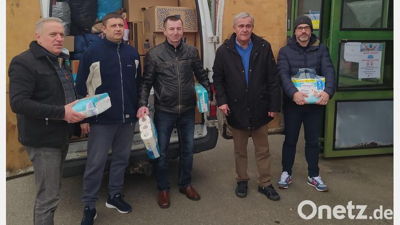 Arkadiy Voloshyn (links), der ukrainische Fahrer Sergej Iwanow (Zweiter v. links) und Waldemar Hock (Mitte) stehen vor dem vollgepackten Bus, der Spenden in die Ukraine bringt. Bild: exb/Neue Zeiten