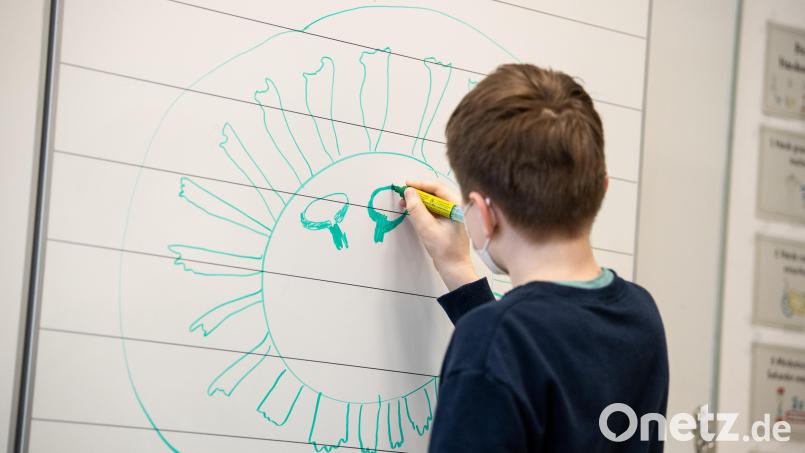 Ein Schüler einer vierten Klasse einer Grundschule zeichnet ein Corona-Virus an die Tafel. Ab kommender Woche fällt in Bayerns Grundschulen die Maskenpflicht. Bild: Matthias Balk/dpa