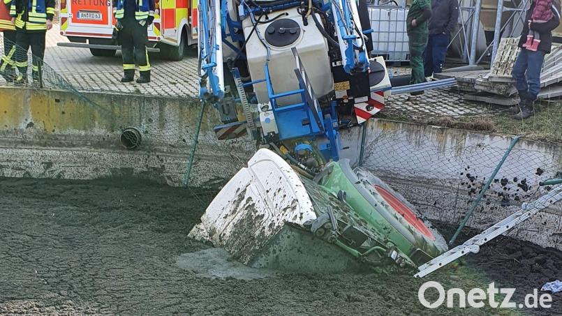 Feuerwehrleute stehen neben einer Güllergrube, in die ein Traktor mit Anhänger gestürzt ist. Bild: Yvonne Jackewitz/Feuerwehr Wald/dpa