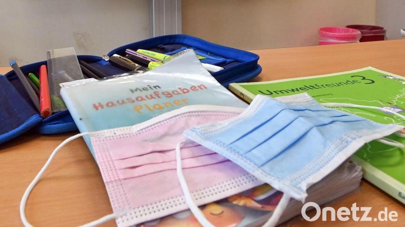 Masken liegen in einem Klassenzimmer auf einem Schulbuch. Bild: Patrick Pleul/dpa-Zentralbild/dpa/Symbolbild