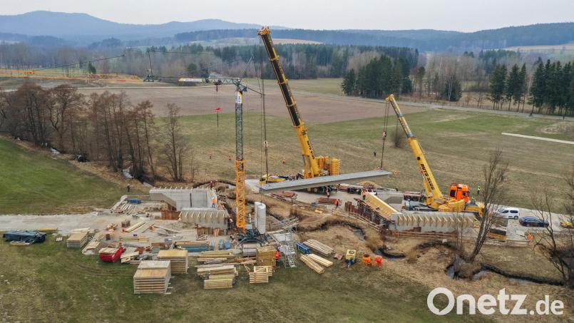 Zwei Kräne hievten am Dienstagnachmittag die rund 29 Meter langen Spannbetonteile auf die Brückenpfeiler über den Kösseinebach. Bild: Florian Miedl/fph