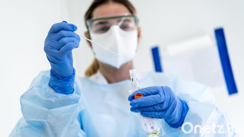 Eine Krankenschwester steckt eine Probe mit einem Nasenabstrich eines Patienten, der auf das neuartige Coronavirus getestet wird, in einen Behälter. Symbolbild: Jean-Christophe Bott/KEYSTONE/dpa