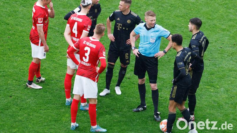 Ratlos nach dem Wechselfehler: Schiedsrichter Christian Dingert (in blau) gemeinsam mit den Bayern und Freiburger Spielern. Bild: Philipp von Ditfurth/dpa
