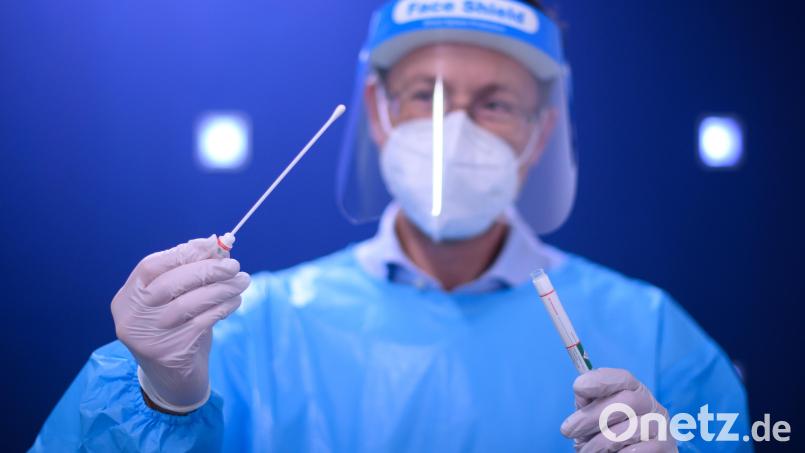 Ein Arzt hält in der Teststation einen Coronavirus-Test in den Händen. Am Freitag, 8. April, gingen die Inzidenzen vier Tage in Folge zurück. Symbolbild: picture alliance/Robert Michael/dpa-Zentralbild/dpa