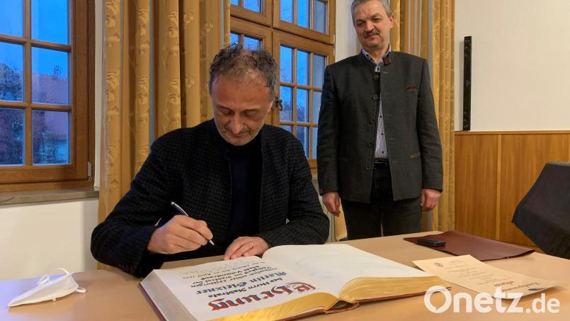 Martin Gleixner ist seit 25 Jahren Mitglied im Vohenstraußer Stadtrat. In der jüngsten Stadtratssitzung erhielt er hierfür von Bürgermeister Andreas Wutzlhofer (im Hintergrund) eine Anerkennungsurkunde und die Pfalzgraf-Friedrich-Medaille in Silber. Der Fraktionsvorsitzende der Freien Wähler verewigte sich im Goldenen Buch der Stadt Vohenstrauß. Bild: ck