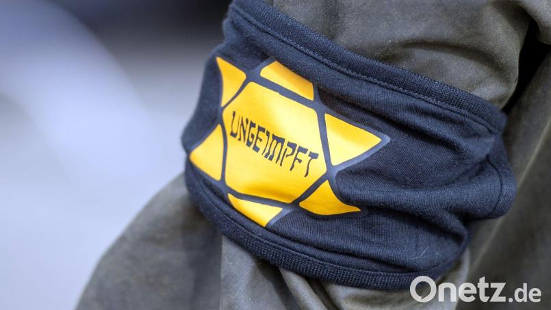 Ein Demonstrant trägt eine Armbinde mit einem gelben Stern, der an einen Judenstern erinnern soll. Bild: Christophe Gateau/dpa/Archivbild