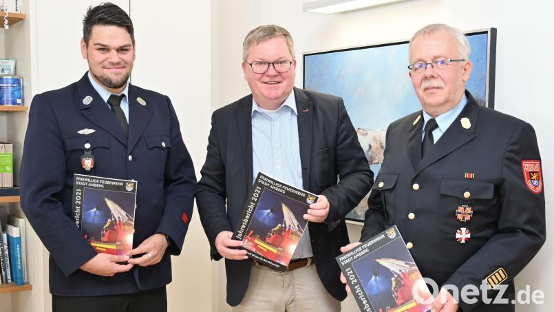 Der neue Stadtbrandrat Heinrich Scharf (rechts) und der stellvertretende Vorsitzende des Feuerwehrvereins, Patrick Wittmann (links), überreichen Oberbürgermeister Michael Cerny das erste Exemplar des Jahresberichts 2021. Bild: Susanne Schwab, Stadt Amberg/exb