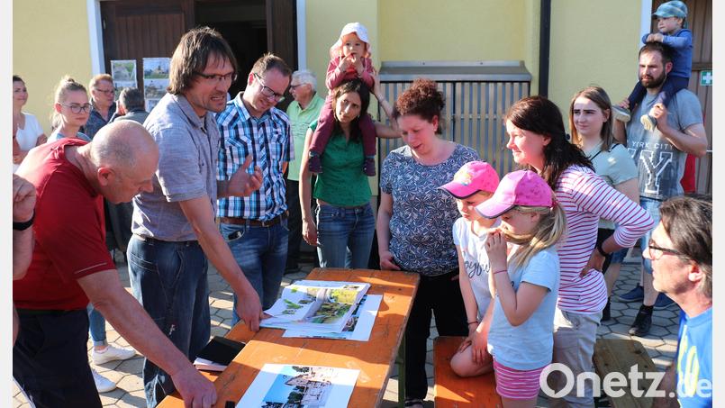 Jörg Band von der Firma Eibe zeigte Beispiele aus dem Katalog, erklärte deren Spielwert und die Altersgruppen, für die die Spielgeräte bestimmt sind. Bürgermeister Roman Schäffler (Mitte) und die Kinder sowie der Eltern folgten aufmerksam seinen Ausführungen. Bild: rpp