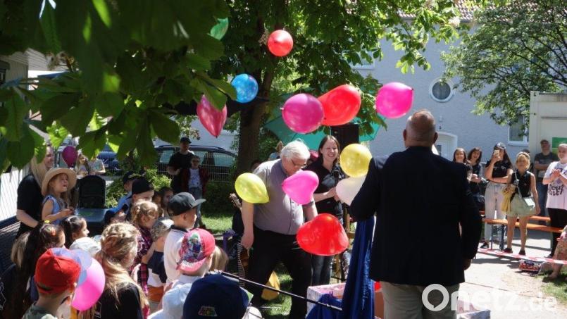 Mit bunten Luftballons begrüßen die Kleinen des Kindergartens Lorenz Werthmann Stadtpfarrer Gottfried Schubach und Siedler-Chef Wolfgang Pausch. Bild: Kunz