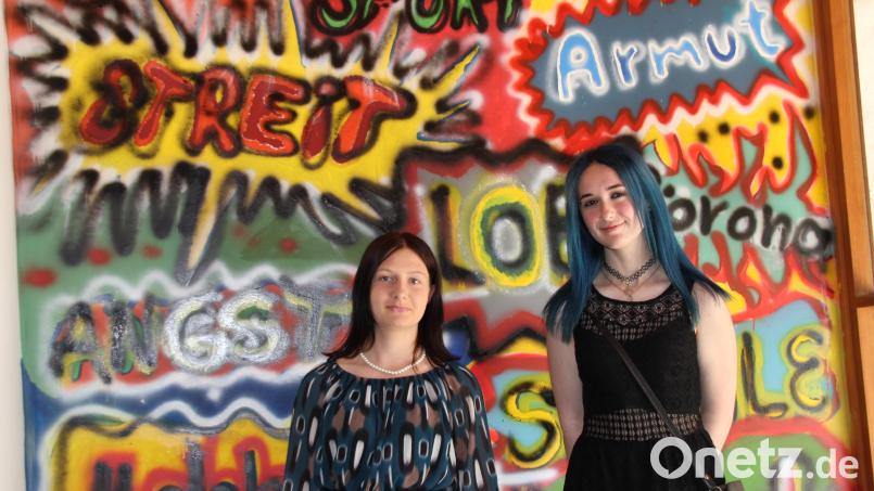 Schülerinnen wurden zu Künstlerinnen. In diesem Fall Nina Brandl (links) und Kim Bedrunka. Sie stehen vor den Graffiti, die nun das Foyer der Erlöserkirche in Amberg zieren. Bild: ads