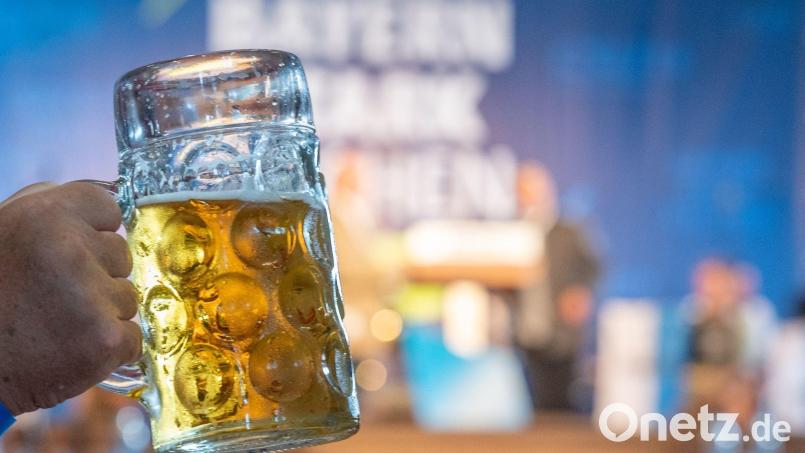 Ein Mann hält eine Maß Bier hoch. Symbolbild: Armin Weigel/dpa