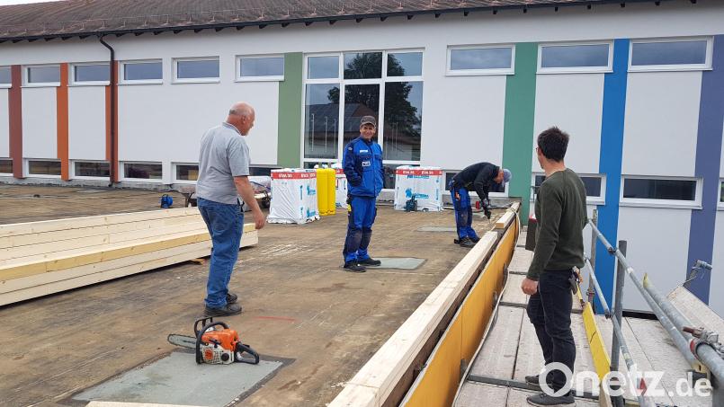 Die Sanierung des Flachdaches des Aula-Gebäudes der Grundschule Moosbach ist voll im Gange; hier die Zimmerei-Firma im Gespräch mit Hausmeister Wolfgang Piehler (links). Bild: gi